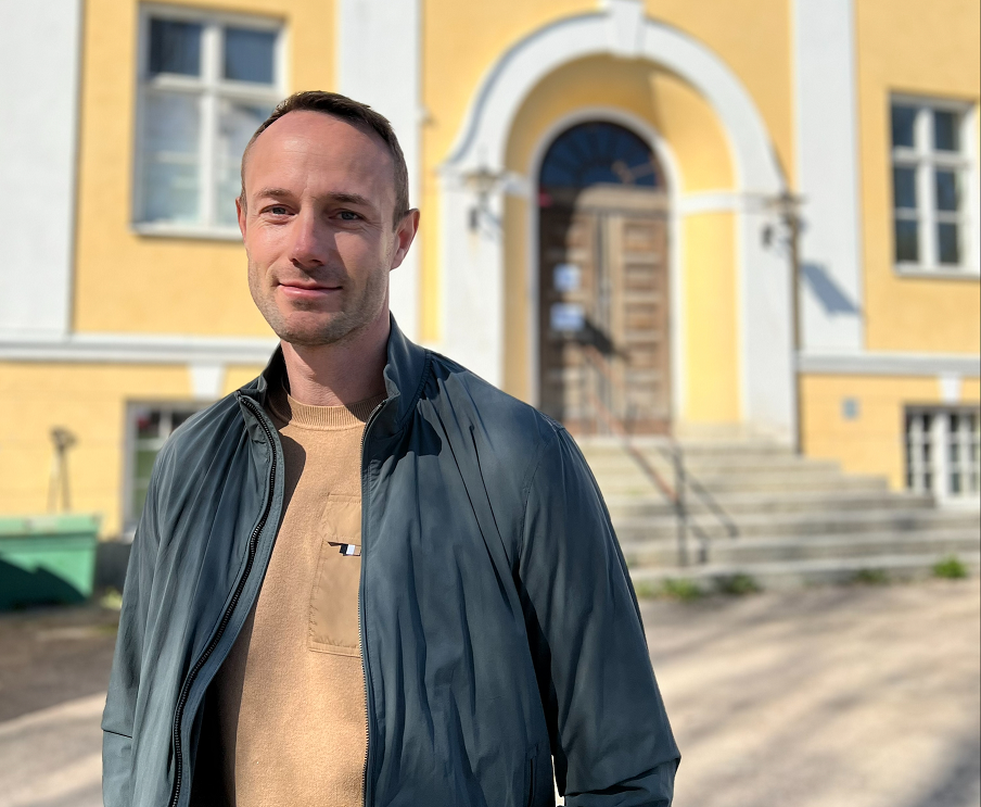 En man som står framför ett gult hus.